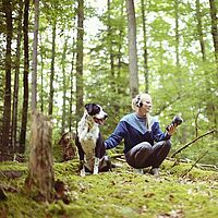 Musikerin her tree mit Hund im Wald bei Aufnahmen
