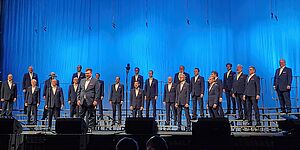 Chor Herrenbesuch auf der Bühne vor einem blauen Vorhang