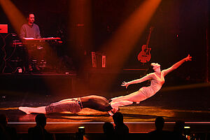 Zwei Akrobaten auf der Bühne mit rotem Licht angestrahlt