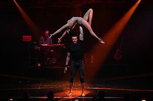 Ein Akrobat hebt eine Akrobatin auf der Bühne empor