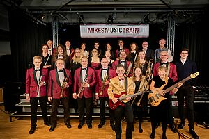 Jazz-Band Mikes Music Train mit roten Sakkos und schwarzen Fliegen vor einer Bühne