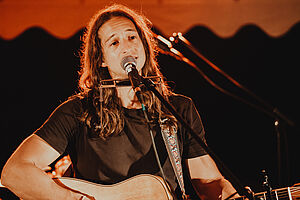 Adam Wendler playing on a guitar while singing 