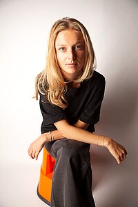 Singer ANNIKA sitting in front of a white wall