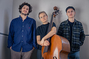 Drei Musiker_innen, eine Mit Kontrabass in der Mitte