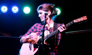 Sängerin Solly Aschkar mit Gitarre hinter Mikrofon