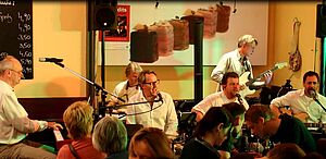 Sechs Musiker auf einer Bühne mit verschiedenen Instrumenten