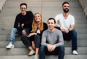 Das Bolandi Trio mit Regy Heiß auf einer grauen Treppe sitzend