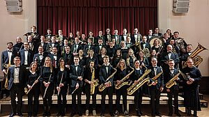 Der Akademische Gesangverein München mit Instrumentalisten vor einer Bühne mit rotem Vorhang 