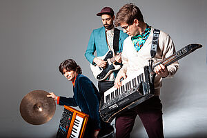 drei Musiker mit E-Gitarre, Keytar und einem Synthesizer