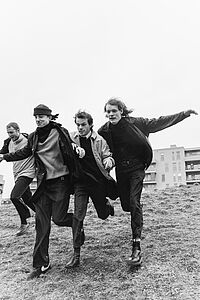 vier laufende Bandmitglieder in schwarz-weiß 